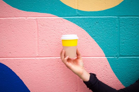 A picture of a bright coffee cup in front of a painted wall